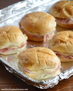 ham and cheese sliders on tin foil lined up in a row, ready to be eaten