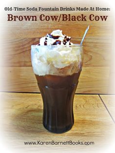 a tall glass filled with brown cow milkshake and topped with whipped cream on top