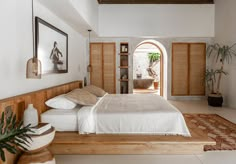 a bedroom with a bed, potted plants and pictures on the wall