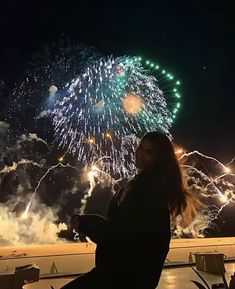 a woman sitting in front of a firework display