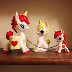 three little pony figurines sitting on top of a wooden table next to each other