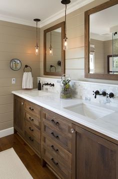 a bathroom with two sinks, mirrors and lights on the wall above them is shown