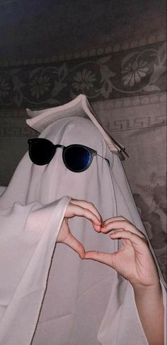 a person wearing sunglasses making a heart shape with their hands