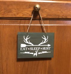 a sign that says eat sleep hunt hanging from a door handle with deer antlers on it