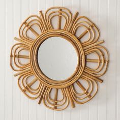 a round mirror hanging on the wall next to a wooden frame and wicker decoration