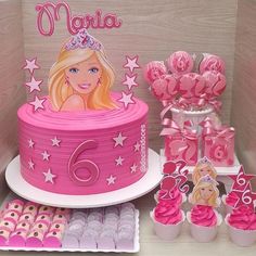 there is a barbie birthday cake and cupcakes on the table