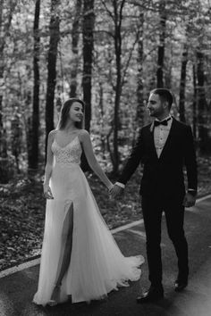 black and white photo of bride and groom holding hands in the woods at their wedding