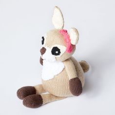 a small stuffed animal with a pink bow on it's head and ears sitting down