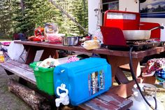 the picnic table is set up with coolers and other camping items on it, including an ice chest