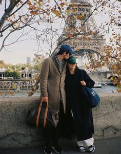 a man and woman standing next to each other near the eiffel tower in paris