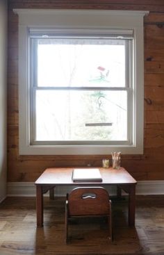 an empty room with a table and chair in the corner, next to a window