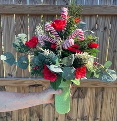 a person holding a vase filled with flowers and candy canes