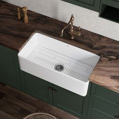 a large white sink sitting on top of a wooden counter next to green cupboards