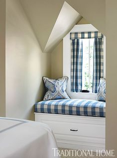 a window seat in the corner of a room with blue and white pillows on it