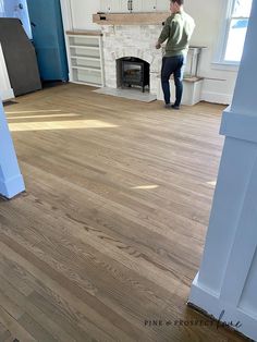 a man standing in the middle of a living room with hardwood floors and white walls