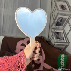 a person holding up a heart shaped mirror