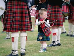 a little boy in a kilt playing the bagpipe