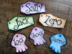 four decorated cookies sitting on top of a wooden table next to each other with names painted on them