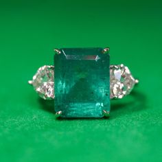 an emerald and diamond ring on a green surface