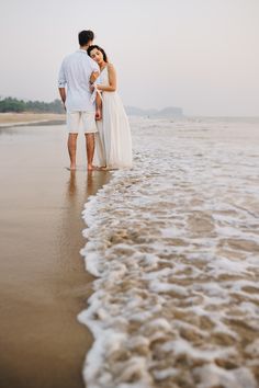 a man and woman are standing in the water at the beach with their arms around each other