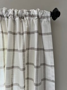 the curtain is pulled back and has a checkered pattern on it, with a black metal hook at the end