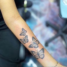 a woman's arm with three butterflies tattooed on the left side of her arm