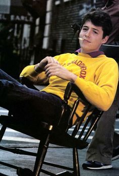 a young man sitting in a rocking chair on the street