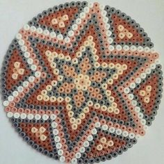 a round beaded coaster with an orange, white and grey flower design on it