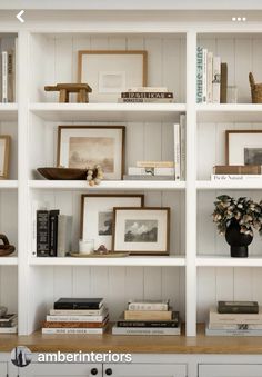 the bookshelf is filled with many different items and pictures on it's white shelves