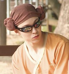 a woman wearing sunglasses and a towel on top of her head, sitting at a park bench