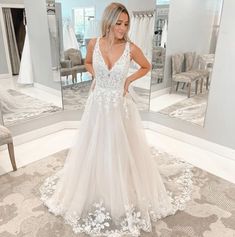 a woman standing in front of a mirror wearing a wedding dress with flowers on it