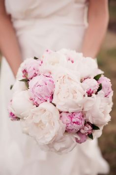 a woman holding a bouquet of pink and white flowers