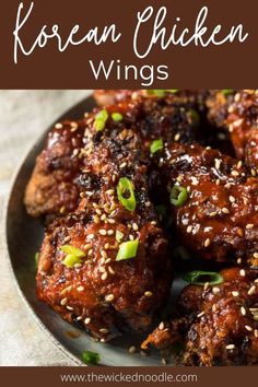 korean chicken wings with sesame seeds and green onions on the side, in a black plate