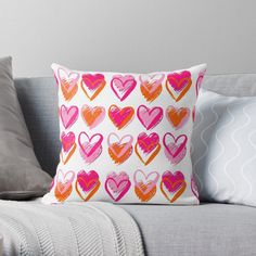 pink and orange hearts on white throw pillow sitting on a gray couch with grey pillows