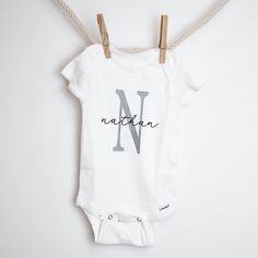 Kick off the baby shower or new born with this adorable custom onesie! Perfect for a baby name's announcement, group event or instagram shoot! This onesie reads the baby's name in a black script font with an uppercase single letter of the first name in rose gold or grey. Black script font with a grey or rose gold initial Handmade Turn inside out with cold wash // Dry on Low No Bleach // Softener ****CUSTOM ORDER**** How it works: When you check out please put your specifications in the NOTES. Th Personalized Fitted Onesie For Gender Reveal, Custom Name White Cotton Onesie, White Custom Name Fitted Onesie, White Fitted Onesie With Custom Name, Baby Onies, Baby Name Onesie, Baby Name Announcement, Rose Gold Initial, Cricut Baby