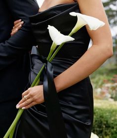 a woman in a black dress holding a white flower