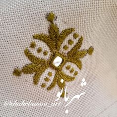 an embroidered snowflake is shown on the side of a white pillow with gold thread