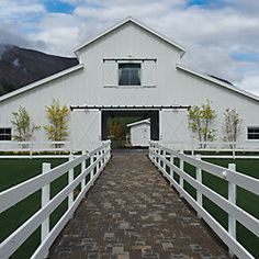 a white barn with a gate leading to the front door and side walk that leads to it