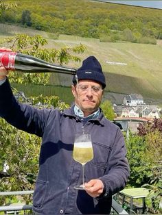 a man holding up a wine glass in front of his face while standing on a balcony