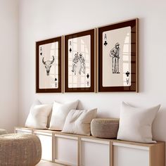 three framed pictures hang on the wall above a bench in a room with white walls