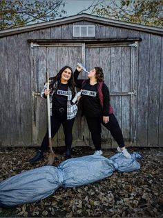 two women standing next to each other in front of a shed with a tarp on the ground