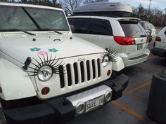 a white jeep parked in a parking lot next to other cars and trucks with decorations on the hood