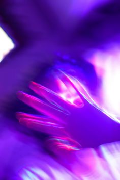 a blurry image of a person's hands with purple and pink lights in the background