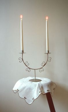 a candle holder with two candles on it and a white table cloth draped over it