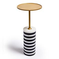 a black and white striped table with a gold plate on it's side stand