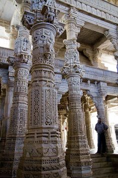 an intricately carved pillar in the middle of a building with two men standing next to it