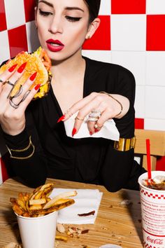 a woman sitting at a table eating a sandwich and french fries in front of her