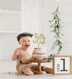 a baby boy sitting in front of a cake