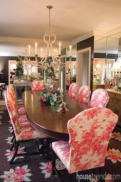 a dining room table with pink chairs and chandelier