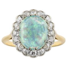 An early 20th century opal and diamond cluster ring, the oval cabochon cut opal measuring approximately 10.7 x 9mm claw set to the centre of an old cut diamond surround, estimated to weigh 0.7 carats in total, in white rub over setting to a yellow gold mount with chenier gallery, circa 1900, later hallmarked 18ct gold London, the head measuring approximately 1.5 x 1.3cm, gross weight 3.78 grams. This ring is in very good condition, the opal bearing small abrasion consistent with the age of the p Antique Opal Ring, Celestial Ring, Contemporary Engagement Rings, Edwardian Jewelry, Diamond Glitter, Unusual Jewelry, Diamond Cluster Ring, Diamond Cluster, Oval Cabochon